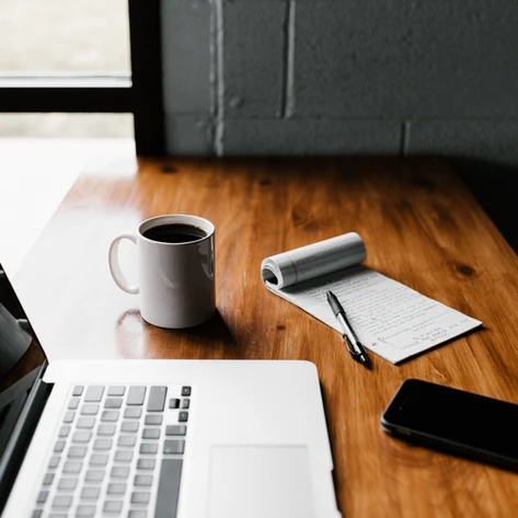 A developer's workspace featuring a laptop, coffee mug, and notepad, symbolizing the process of learning new programming languages.